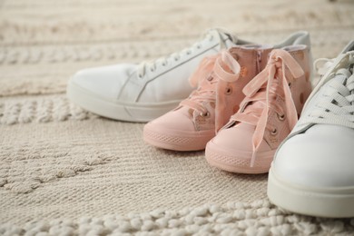 Photo of Big and small sneakers on beige carpet