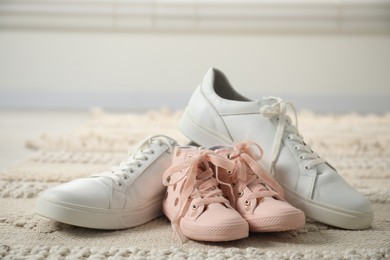 Photo of Big and small sneakers on carpet indoors