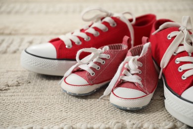 Photo of Big and small sneakers on beige carpet