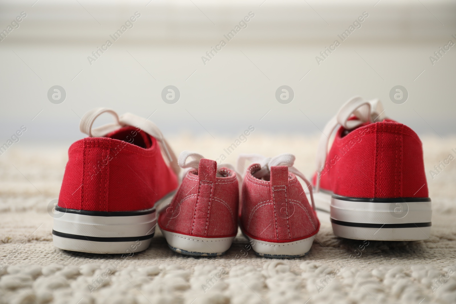 Photo of Big and small sneakers on carpet indoors