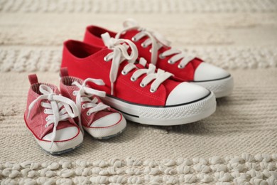 Photo of Big and small sneakers on beige carpet