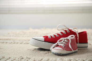 Photo of Big and small sneakers on carpet indoors. Space for text