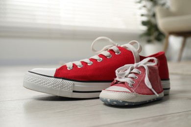 Photo of Big and small sneakers on floor indoors