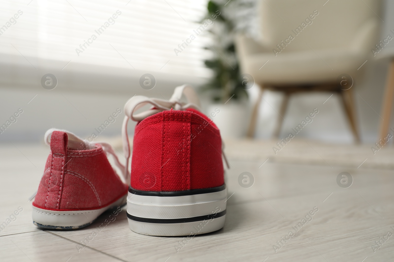 Photo of Big and small sneakers on floor indoors, space for text