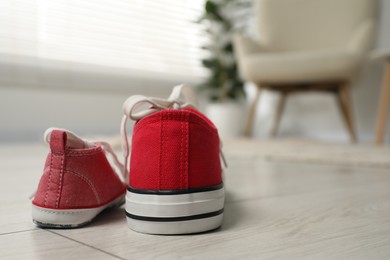 Big and small sneakers on floor indoors, space for text