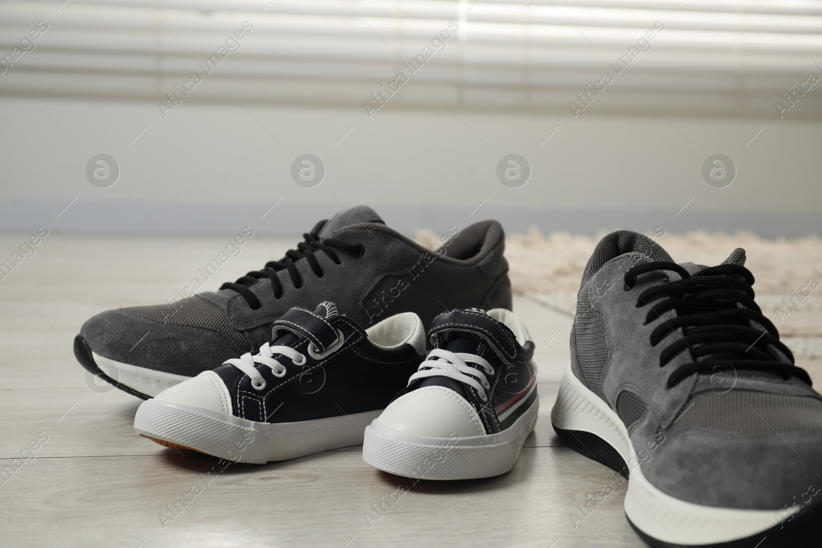 Photo of Big and small sneakers on floor indoors