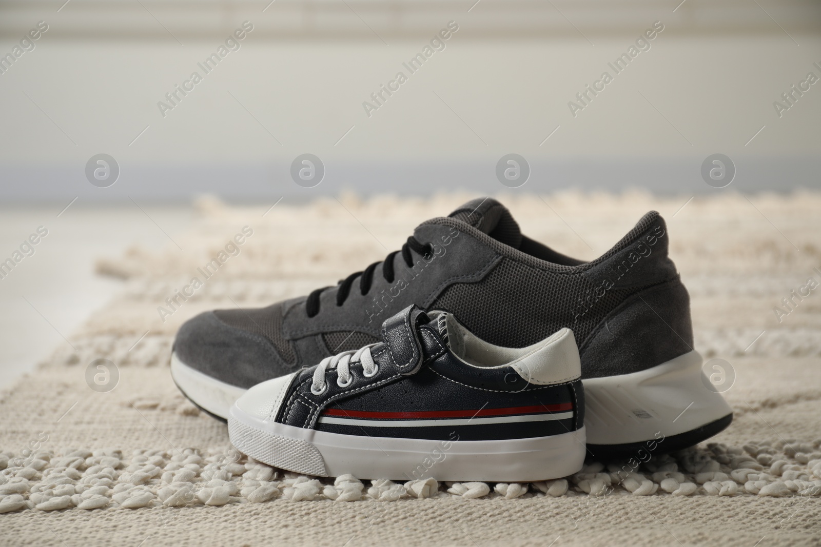 Photo of Big and small sneakers on carpet indoors, closeup