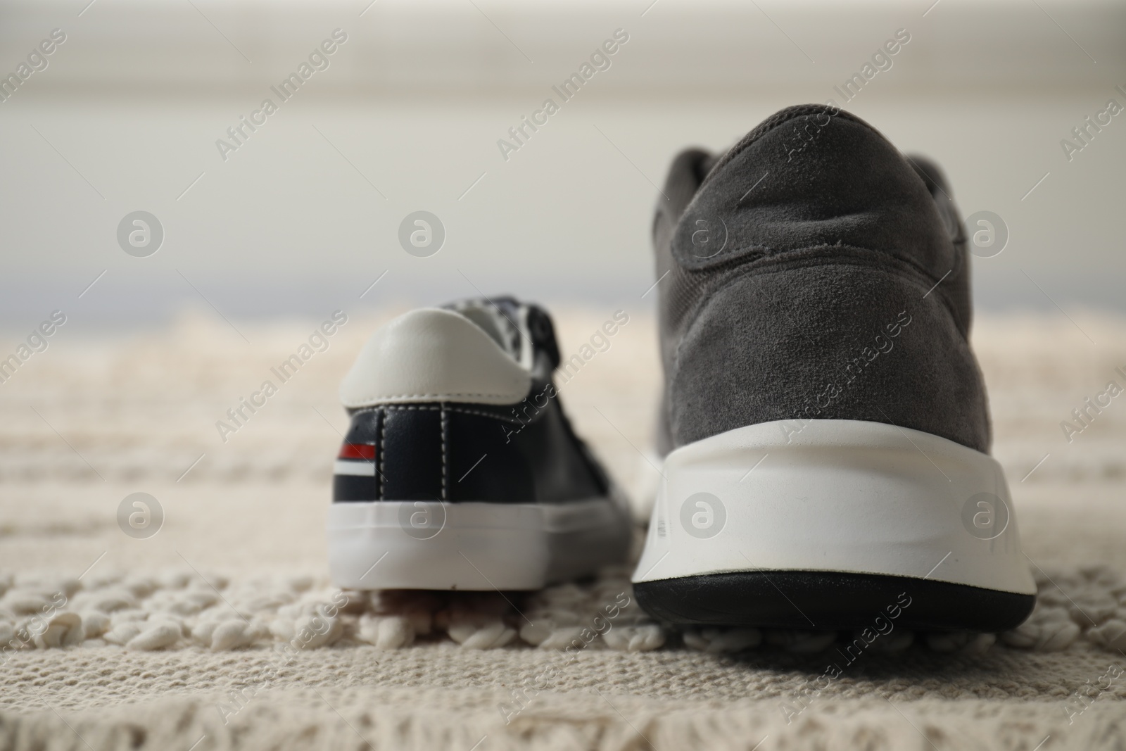 Photo of Big and small sneakers on carpet indoors, closeup