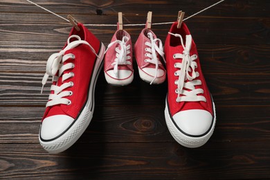 Big and small sneakers hanging on wooden background