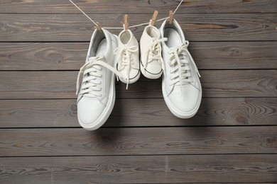 Photo of Big and small sneakers hanging on wooden background