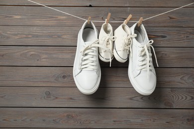 Photo of Big and small sneakers hanging on wooden background