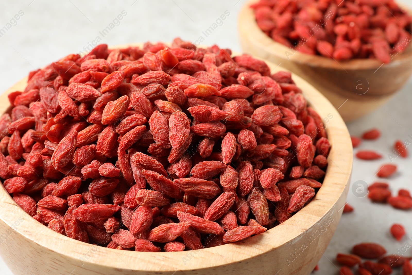Photo of Dried goji berries in bowl on light table, closeup