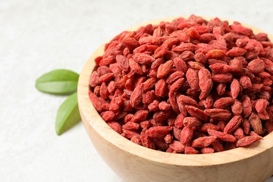 Photo of Dried goji berries in bowl on light table, closeup