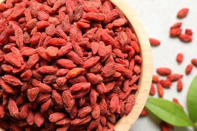 Dried goji berries in bowl on light table, flat lay