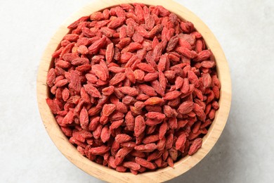 Photo of Dried goji berries in bowl on light table, top view