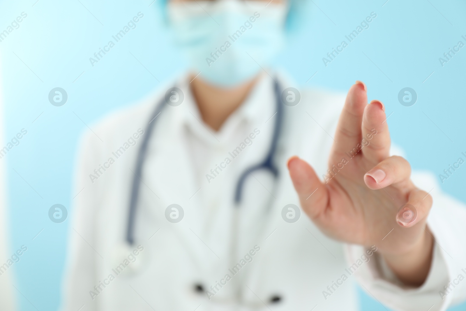 Photo of Doctor holding something on light blue background, closeup. Space for text