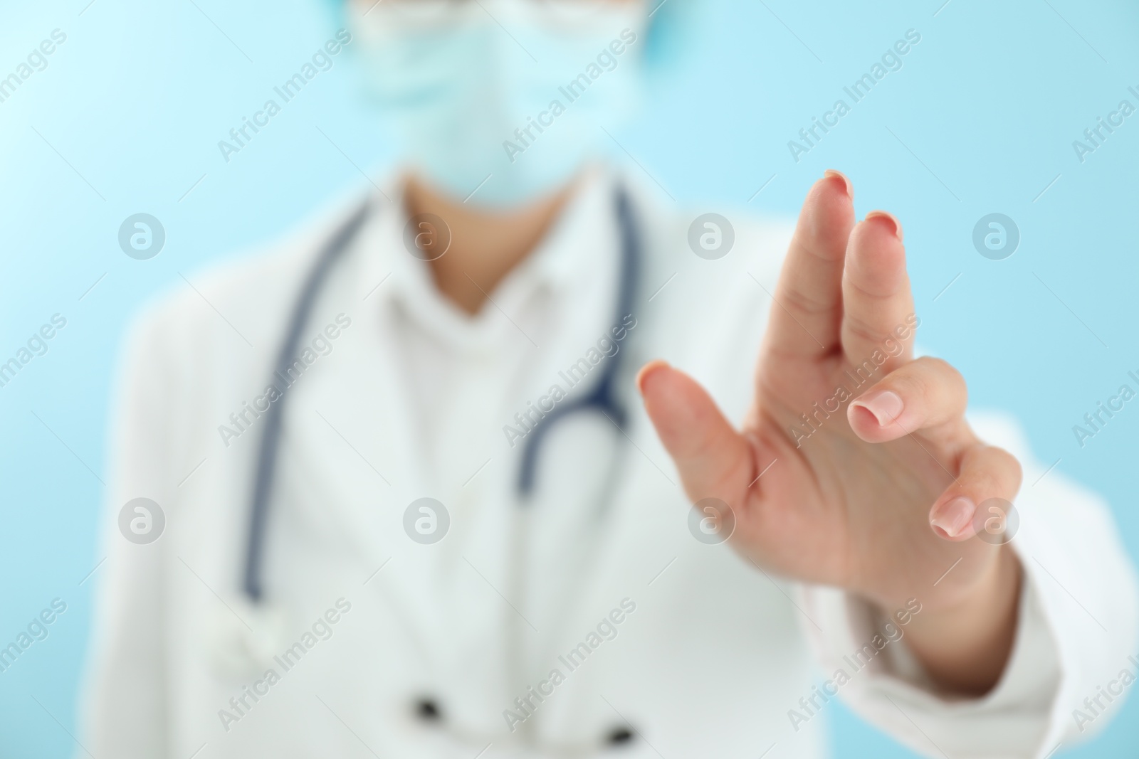 Photo of Doctor holding something on light blue background, closeup. Space for text