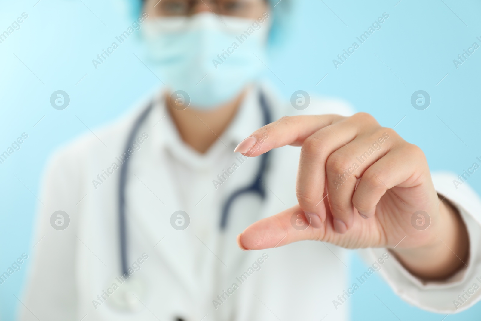 Photo of Doctor holding something on light blue background, closeup. Space for text