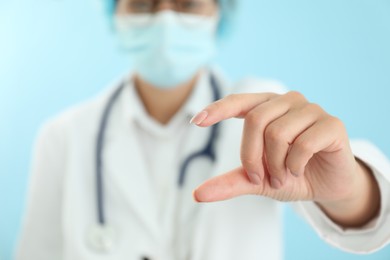 Photo of Doctor holding something on light blue background, closeup. Space for text