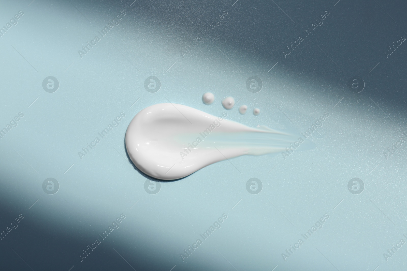 Photo of Sample of face cream on light blue background, top view