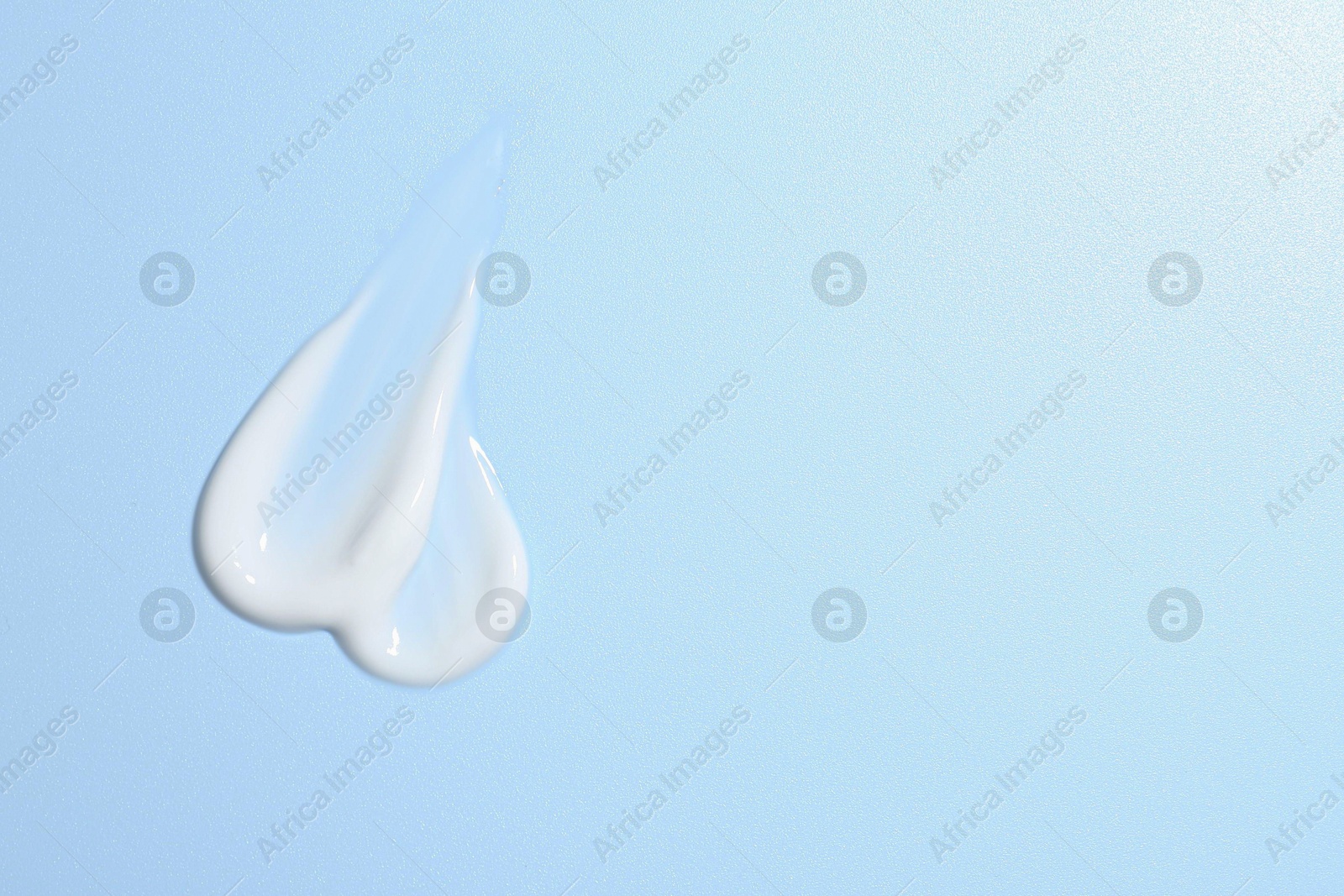 Photo of Sample of face cream on light blue background, top view. Space for text