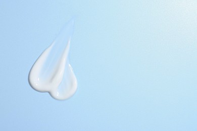 Photo of Sample of face cream on light blue background, top view. Space for text