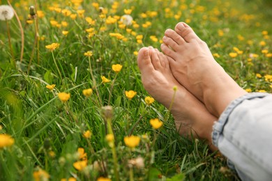 Photo of Woman sitting barefoot on green grass outdoors, closeup. Space for text