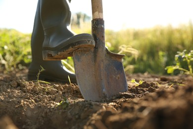 Farmer digging soil with shovel on sunny day, closeup