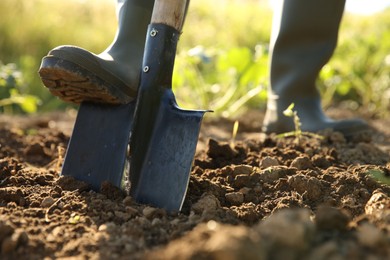 Farmer digging soil with shovel on sunny day, closeup