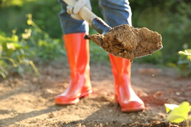 Farmer digging soil with shovel on sunny day, closeup