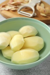 Fresh raw potatoes in bowl on light grey table, closeup