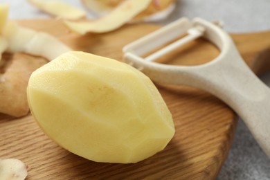 Photo of Fresh raw potato and peeler on table, closeup