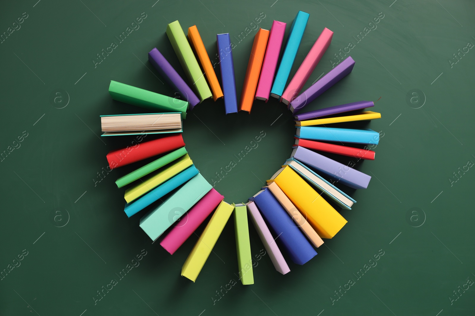 Photo of Heart made of many colorful books on green background, flat lay