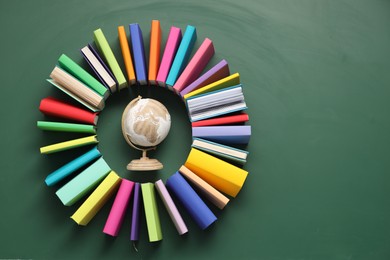 Photo of Globe surrounded by many colorful books on green background, flat lay. Space for text