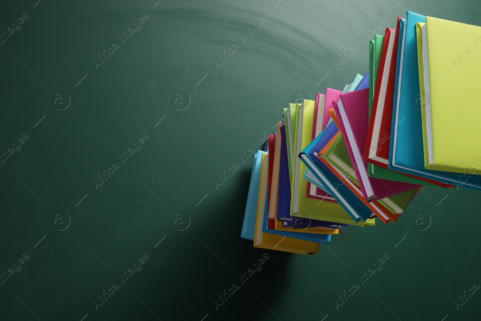 Photo of Stack of many colorful books on green background, above view. Space for text