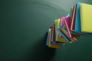 Stack of many colorful books on green background, above view. Space for text