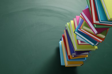 Stack of many colorful books on green background. Space for text