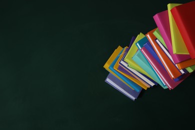 Photo of Stack of many colorful books on green background, above view. Space for text