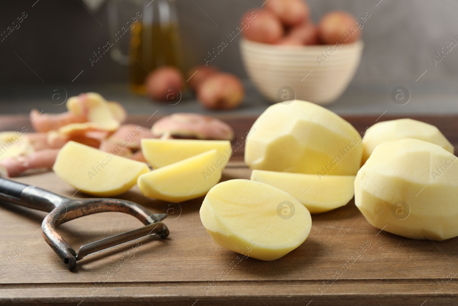 Photo of Fresh raw potatoes and peeler on table