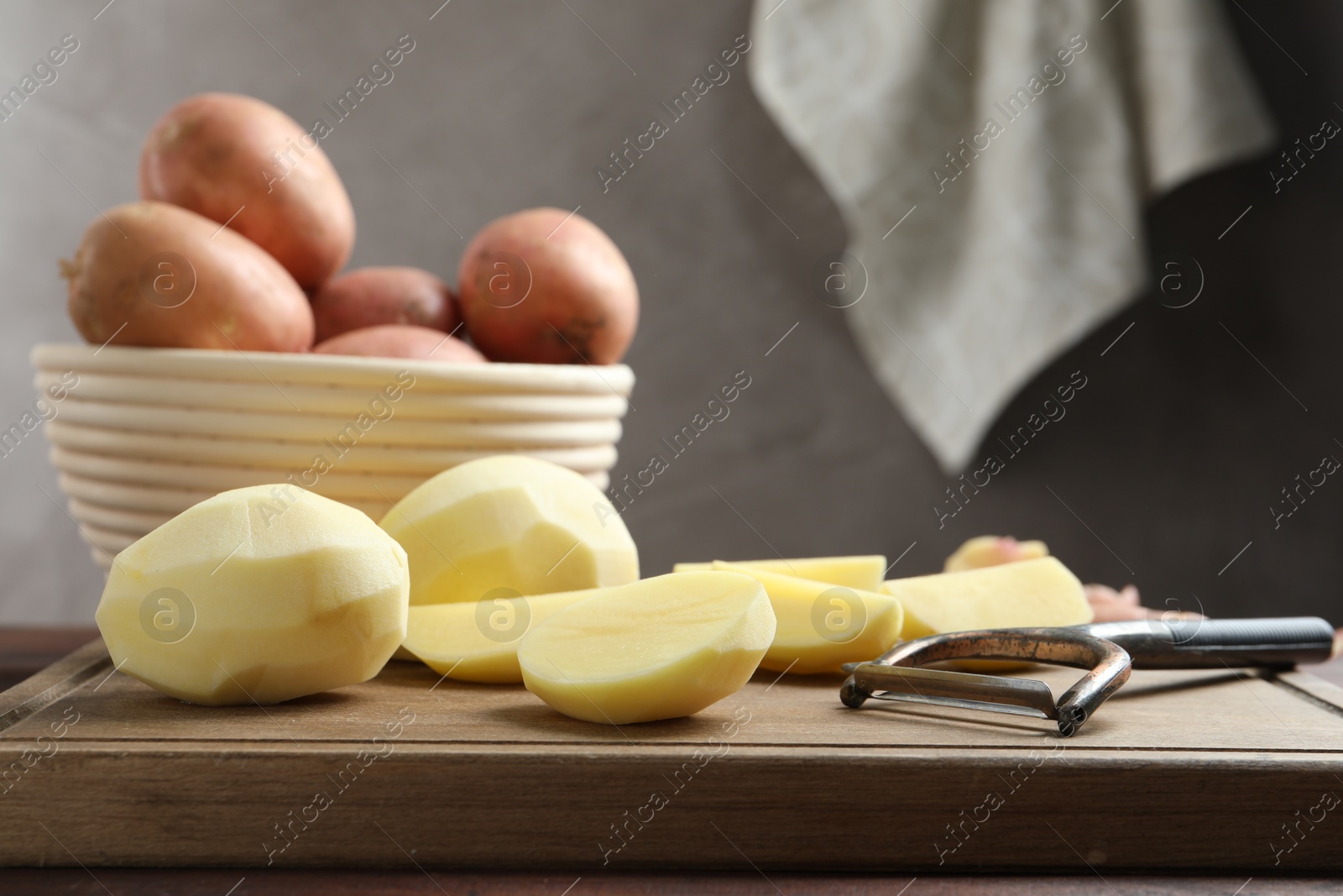 Photo of Fresh raw potatoes and peeler on table