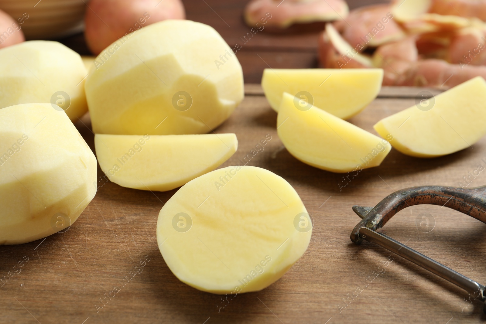 Photo of Fresh raw potatoes and peeler on table