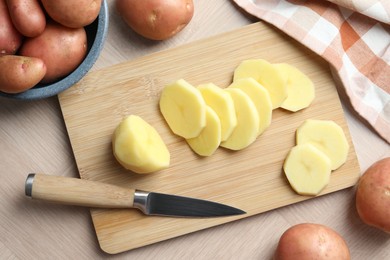 Photo of Fresh raw potatoes and knife on wooden table, top view