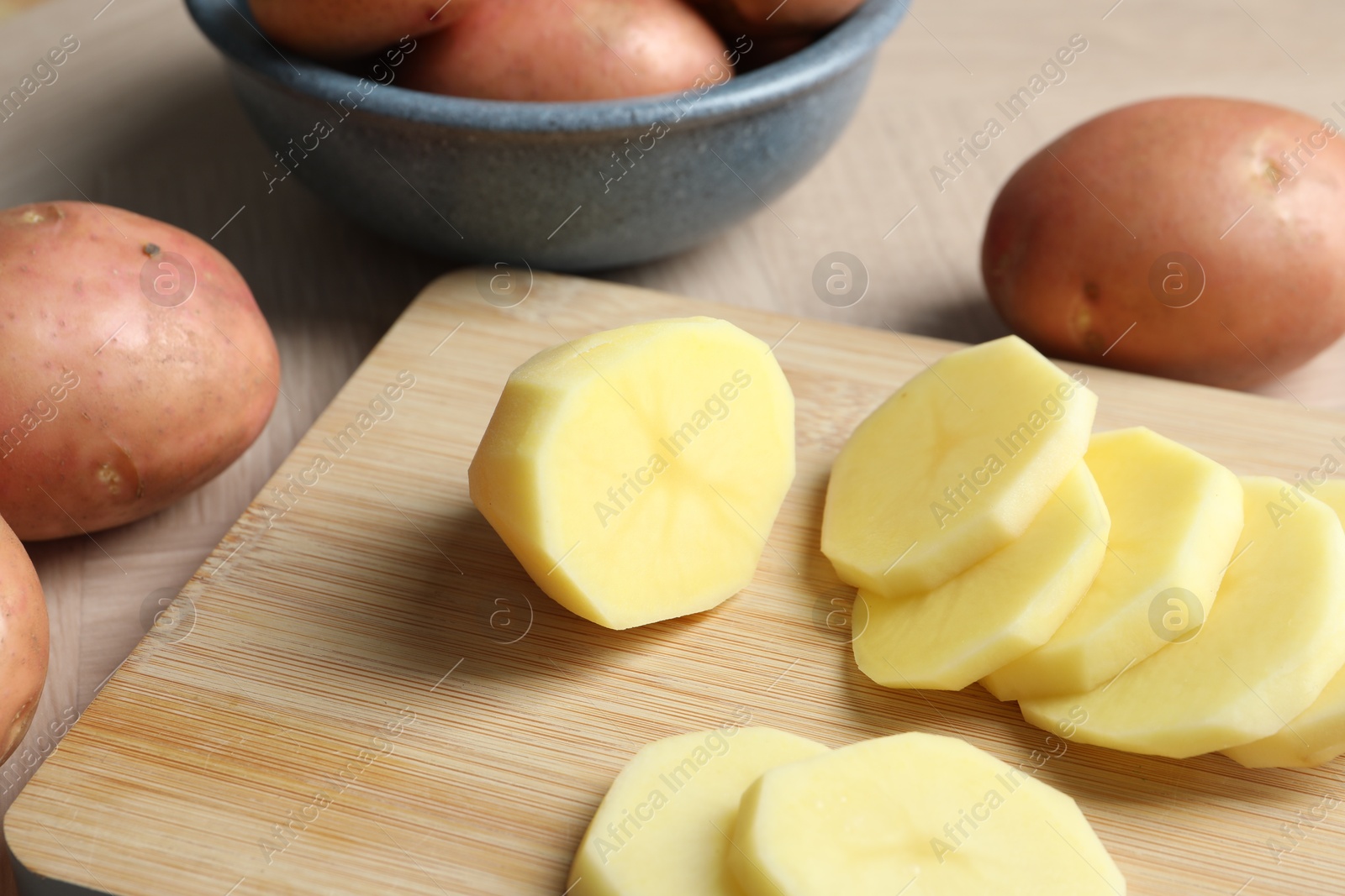 Photo of Whole and cut fresh raw potatoes on wooden table