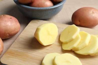 Whole and cut fresh raw potatoes on wooden table