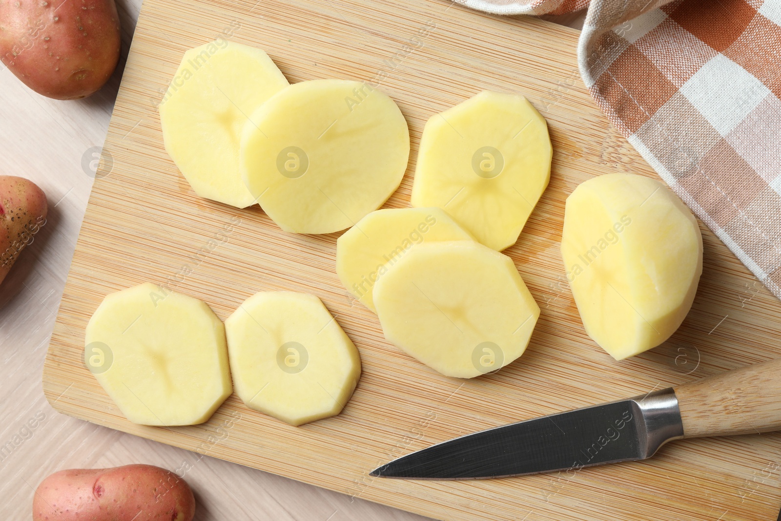 Photo of Fresh raw potatoes and knife on wooden table, top view