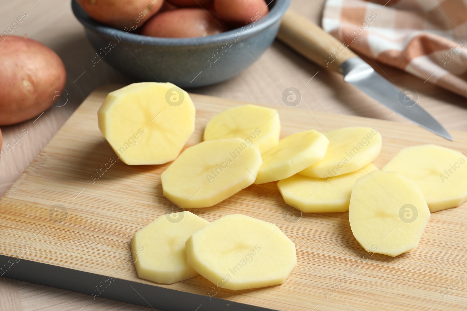 Photo of Fresh raw potatoes and knife on wooden table