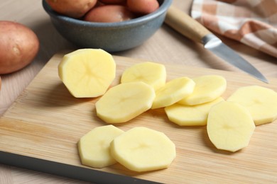 Fresh raw potatoes and knife on wooden table