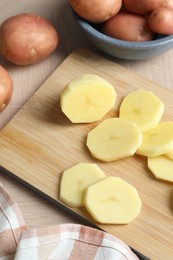 Photo of Whole and cut fresh raw potatoes on wooden table