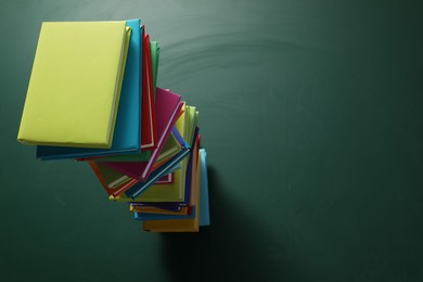 Photo of Stack of many colorful books on green background, above view. Space for text