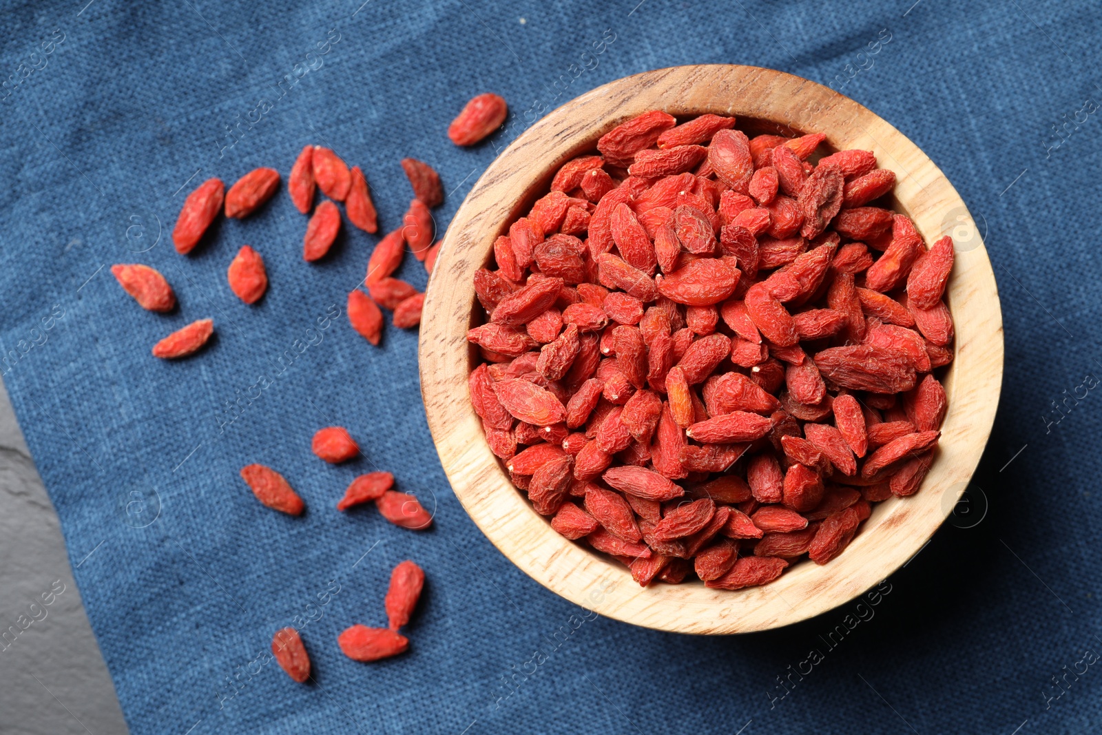 Photo of Dried goji berries on blue cloth, top view